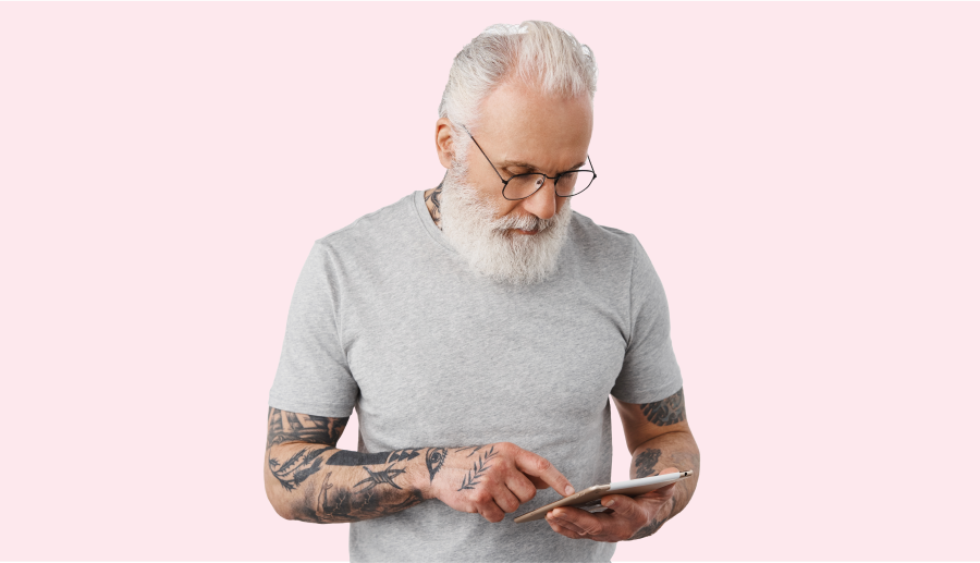 old-man-with-tattoos-reading-news-shopping-online-gadget-standing-against-white-wall